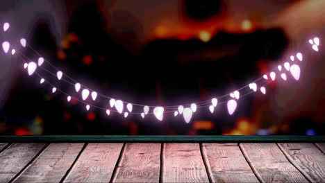 Glowing-pink-fairy-light-decoration-hanging-over-textured-wooden-plank