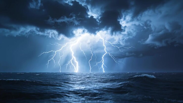 Nuvole temporalesche cariche che sprigionano molti fulmini sull'oceano aperto di notte, riflessi del mare.