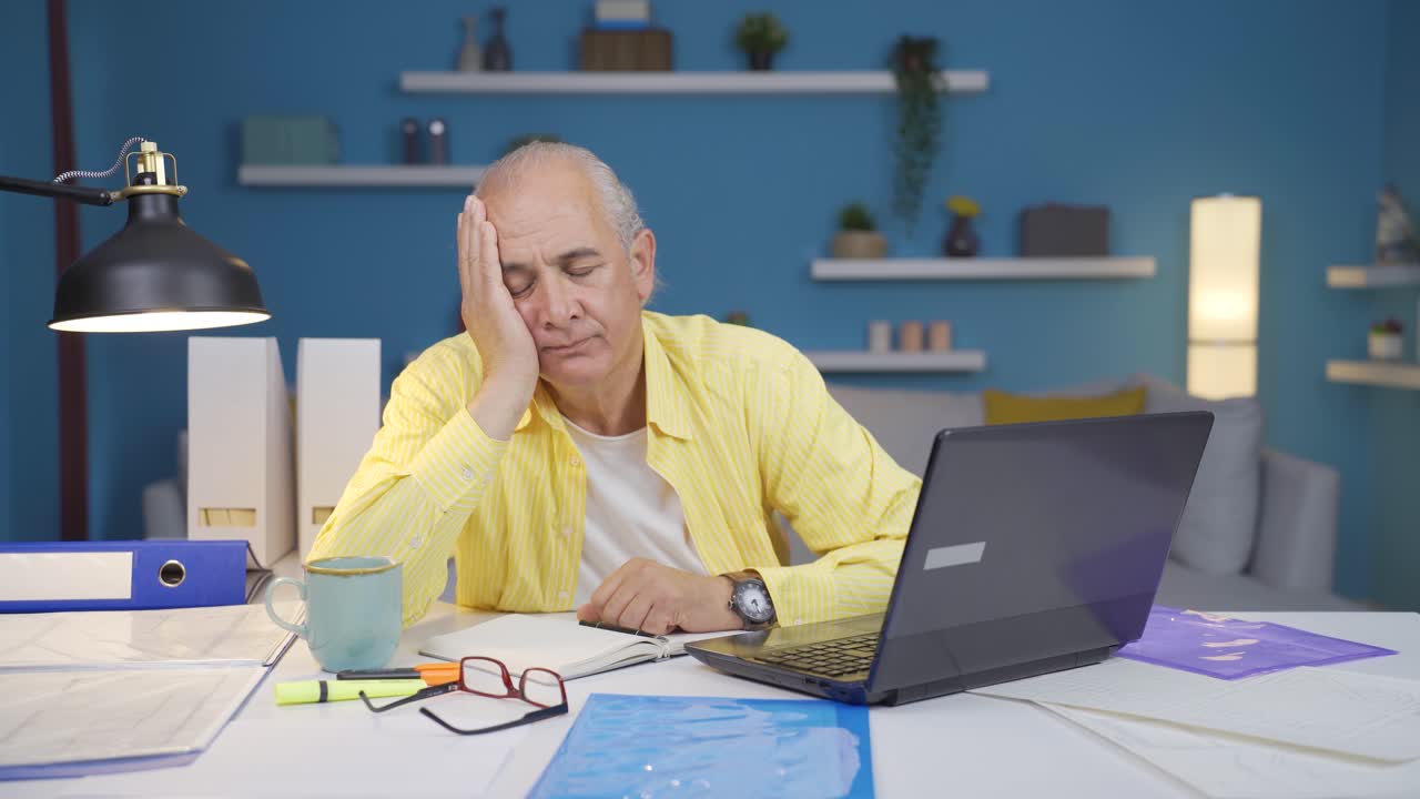 Anziano lavoratore da casa, depresso, che guarda la fotocamera.