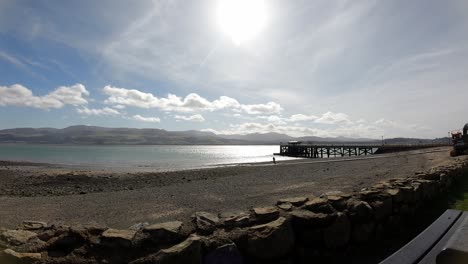 Bright-sunny-Wales-UK-mountain-pebble-coastline-skyline-timelapse-over-Beaumaris-pier