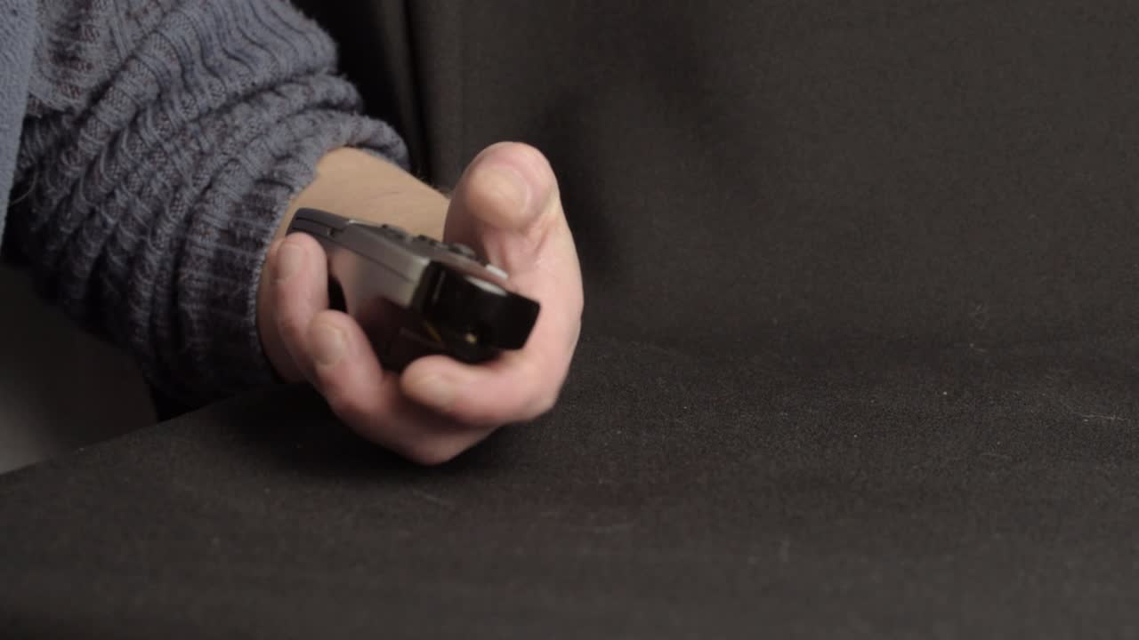 Hand using remote control to change channel close up shot