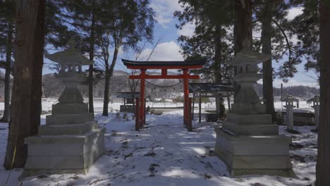en medio de un pequeño santuario forestal, una puerta tradicional japonesa revela un espectacular espectáculo de invierno cuando se abre para revelar el vasto e impresionante paisaje de nieve y montañas en hakuba