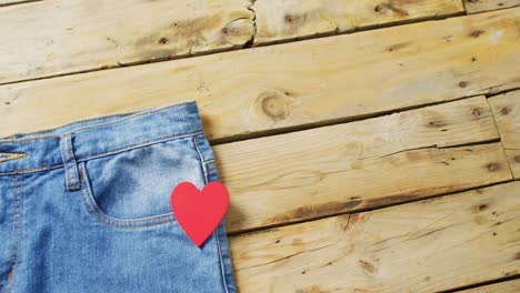 close up of jeans with red heart on wooden background with copy space