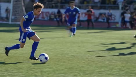 dynamic video still of a soccer match, capturing a player in blue mid-action