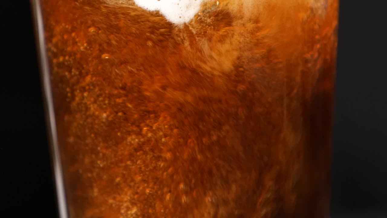 Slow motion coffee pouring and swirling in glass, rich and aromatic