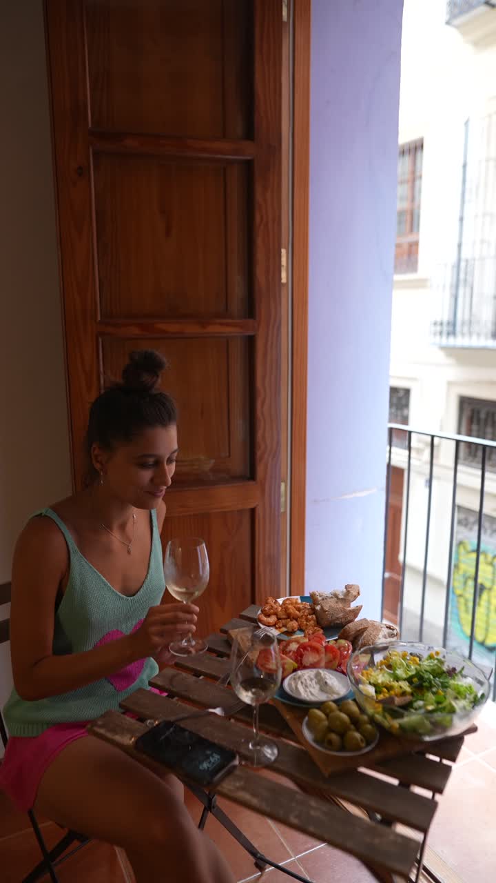 Mulher apreciando uma refeição com vinho em uma varanda