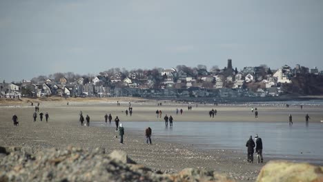 people walking on a beach with a town in the background