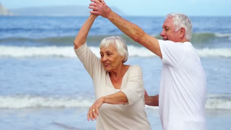 Happy-senior-couple-dancing-on-the-beach