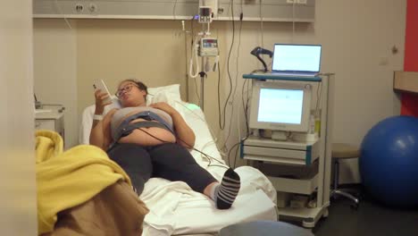 Pregnant-woman-laying-on-hospital-bed-on-a-monitor-to-check-the-pregnancy-status