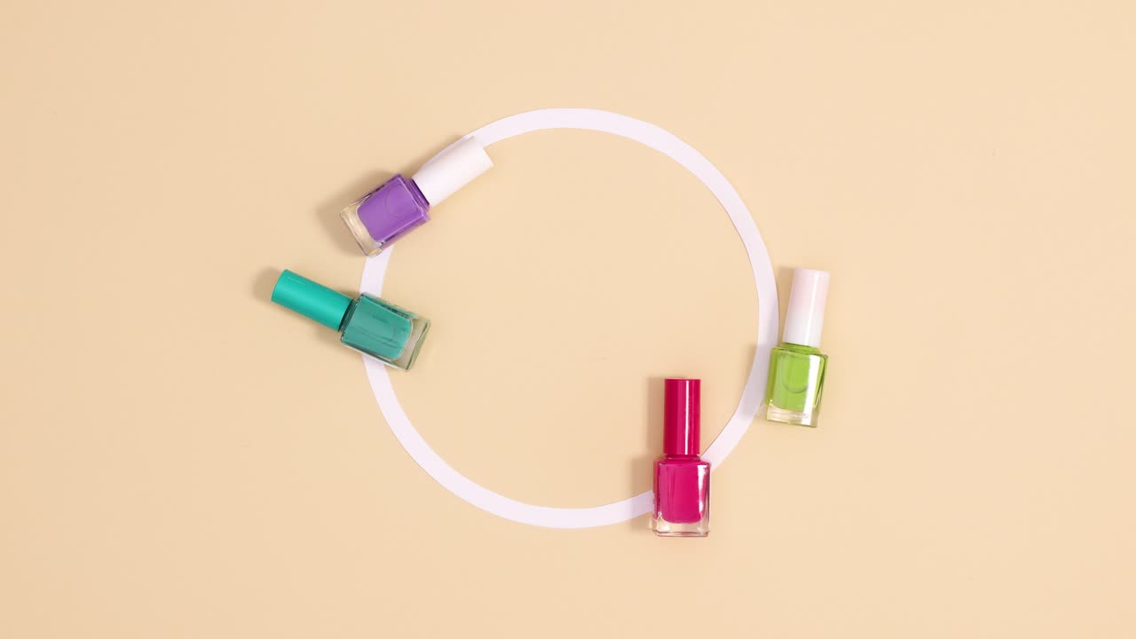las botellas de esmalte de uñas de colores pastel se mueven alrededor del círculo de espacio de copia en fondo beige. detenga el movimiento