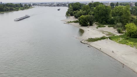 Bedrohlicher-Schuss-über-Einem-Fluss-In-Deutschland-Mit-Breiten-Ufern-Und-Einer-Ladung-Boote,-Rhein-Bei-Köln