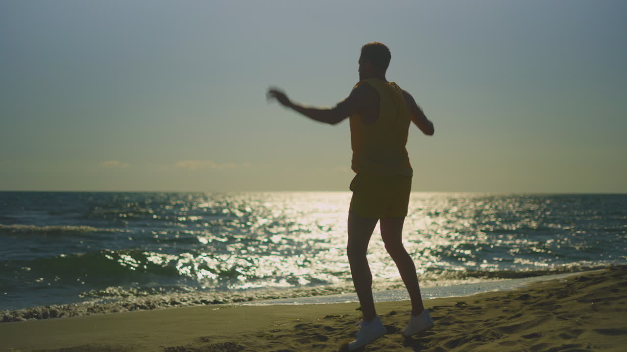 해가 지면 해변에서 춤을 추는 남자