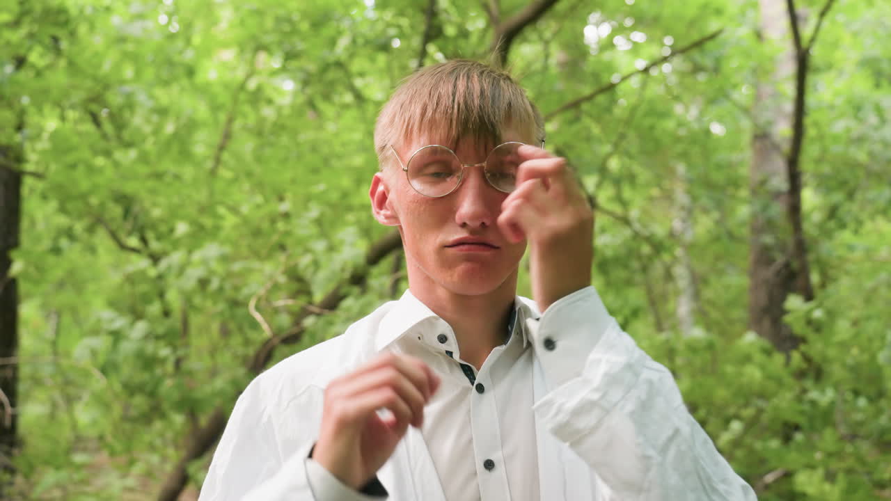 Close view of ecologist in white coat standing in forest removing glasses, surrounded by lush greenery and natural light, highlighting outdoor preparation, concentration, and lifestyle detail
