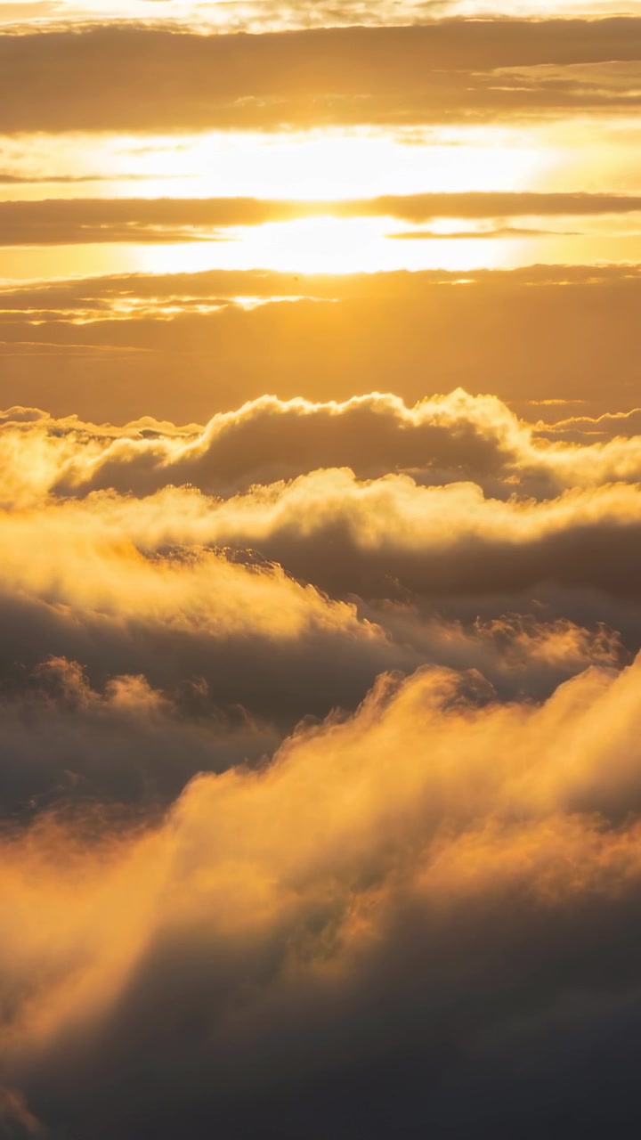 Vertikales Video: Sich verschiebende goldene Wolken und tiefe Sonne, die eine hohe Wolkendecke mit dünnen, sich bewegenden Schichten erwärmt.