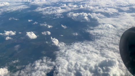 toma de arriba hacia abajo de la vista de la ventana del avión que muestra las nubes voladoras y el valle rural en segundo plano