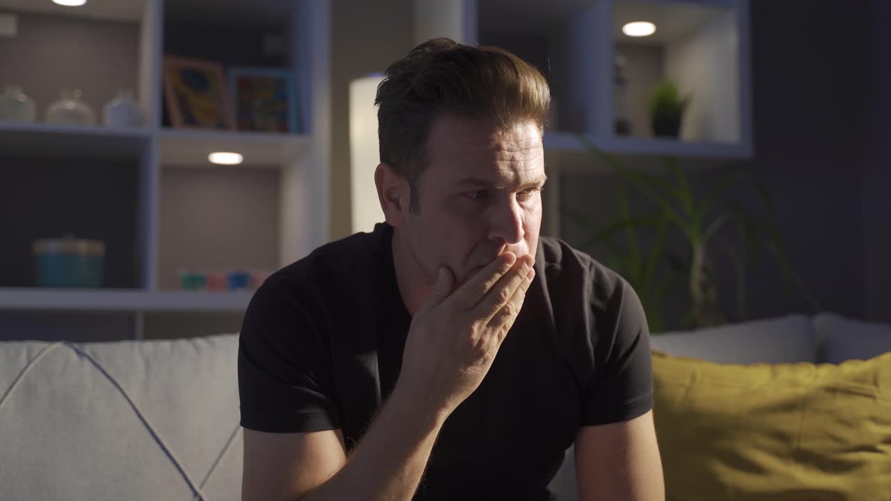 후회하고 사려 깊은 남자가 집에 혼자 있습니다.