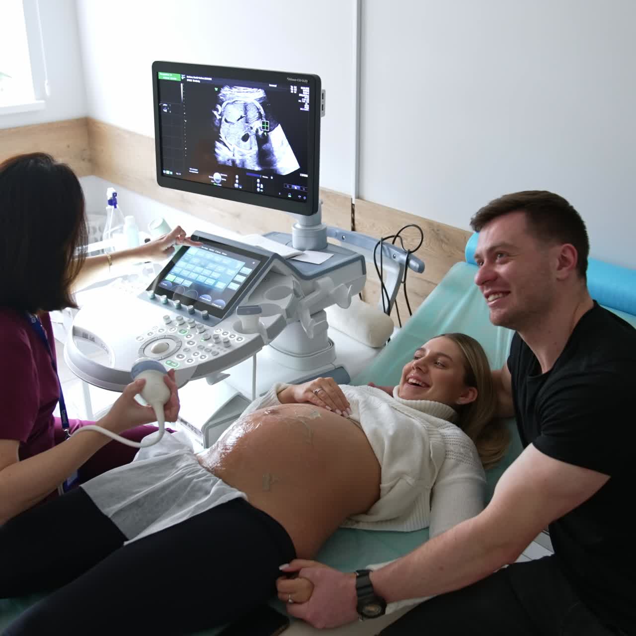 Happy married couple expecting a child at doctor's. Ultrasound ...