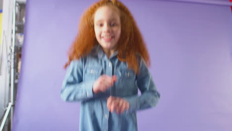 Studio-Portrait-Of-Girl-With-Red-Hair-Dancing-Against-Purple-Background