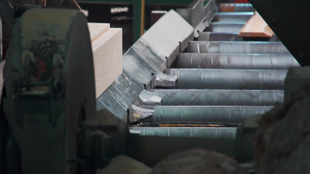 Close up of machine making logs into lumber, long planks being cut in sawmill