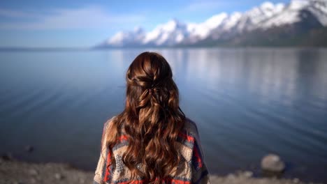 vista increíble una joven morena atractiva parada frente al agua mirando a lo lejos con el telón de fondo de un lago