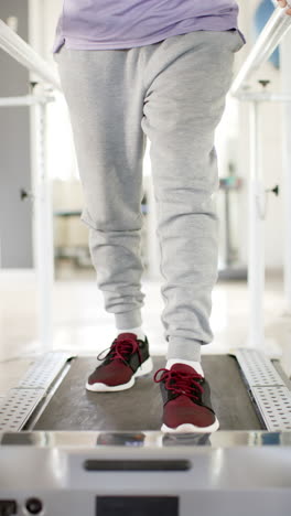 vertical video: walking on treadmill with prosthetic legs, person in rehabilitation therapy
