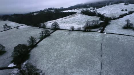 Luftdrohnenaufnahme,-Die-Nach-Oben-Schwenkt,-Um-Die-Wundervolle-Schneebedeckte-Englische-Landschaft-Freizulegen,-Während-Kinder-Und-Erwachsene-Den-Hügel-Hinunter-Rodeln