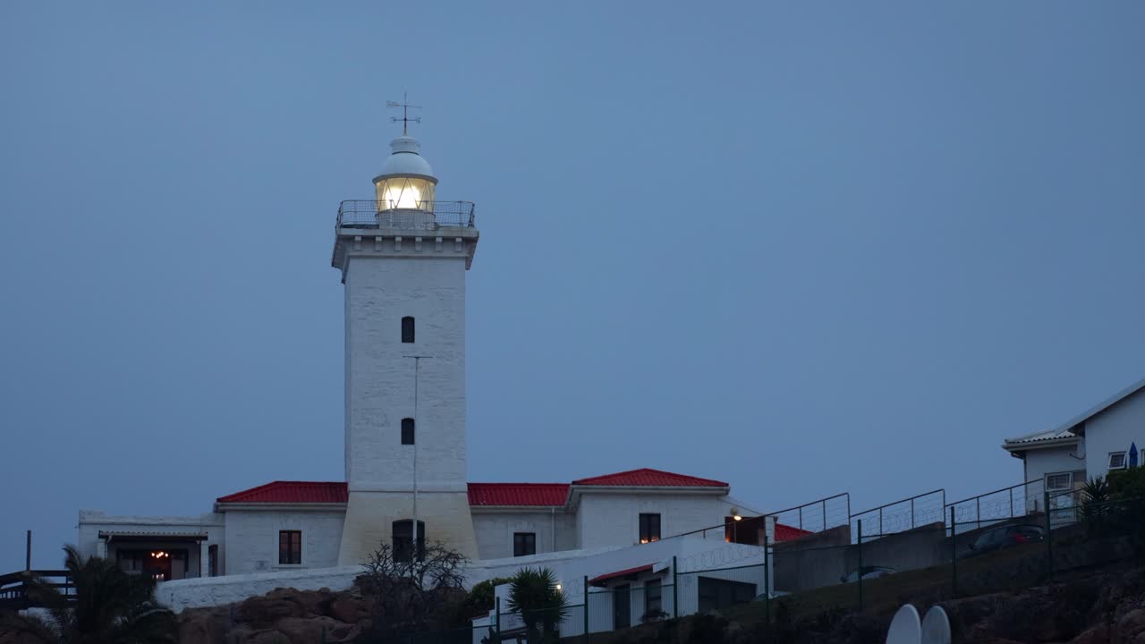 Crepuscolo durante l'ora blu al faro, luce che ruota lentamente in cima, spazio per il testo