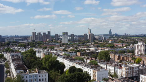 Aerial-view-of-residential-town-district.-Tall-buildings-in-distance.-Landing-footage-between-houses.-London,-UK