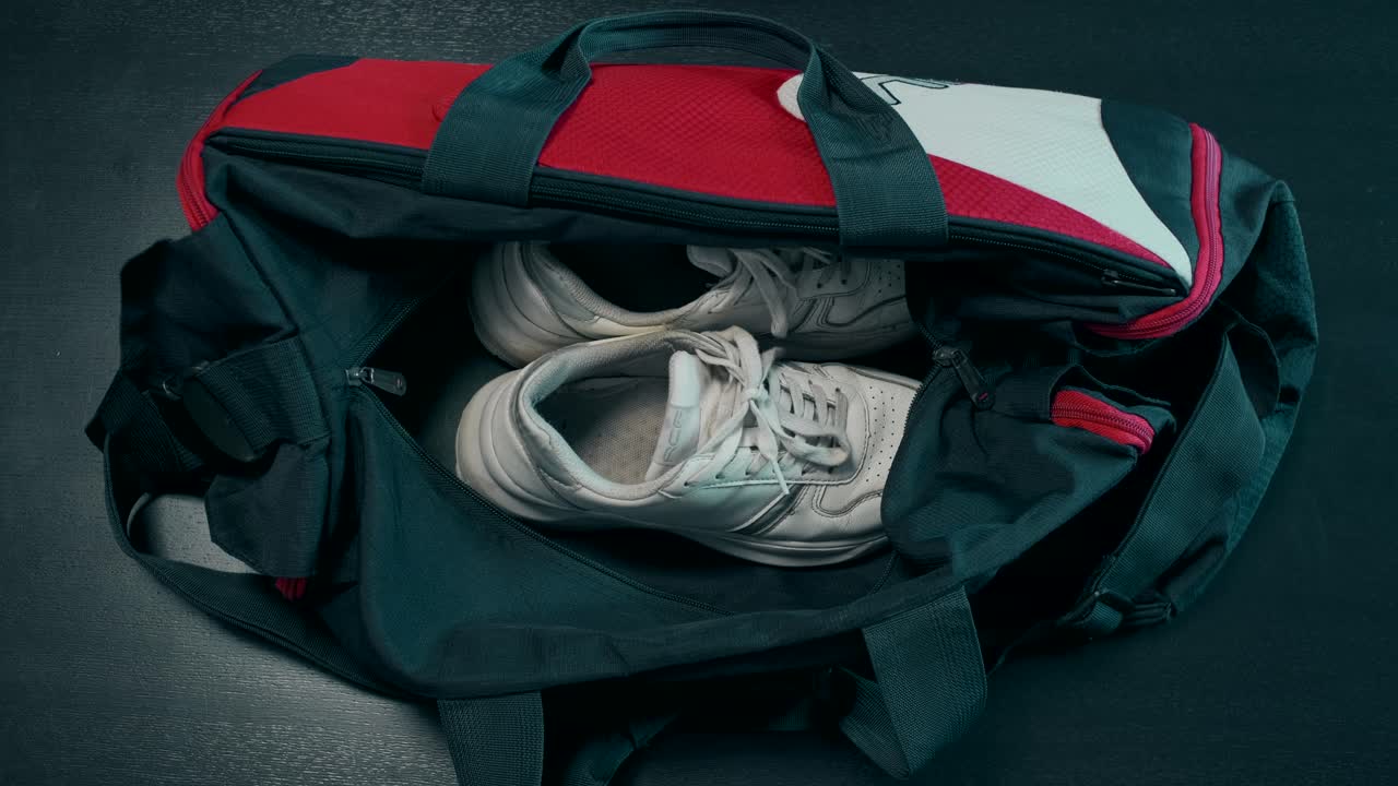 Osoba balící žlutou látku do sportovní tašky