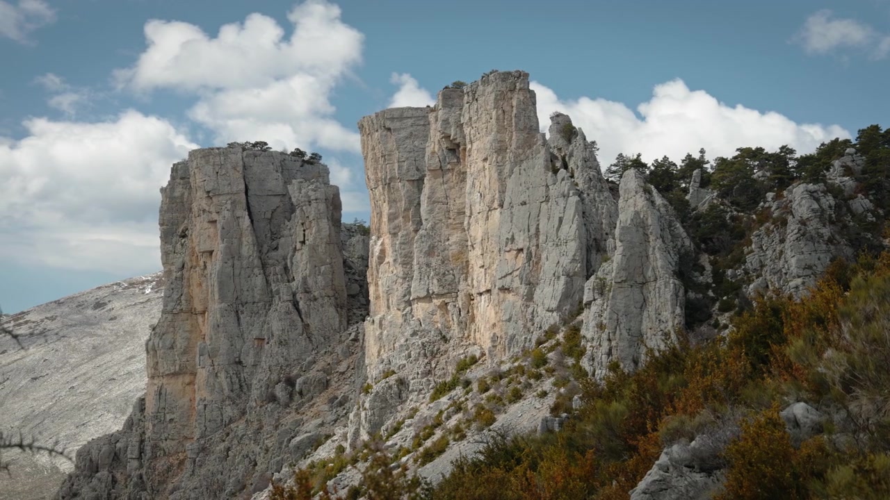Les falaises abruptes et impressionnantes du sommet des Cadières de Brandis en France. Les falaises escarpées plongent directement dans les profondeurs. Le ciel bleu est couvert de légers nuages et le soleil brille.