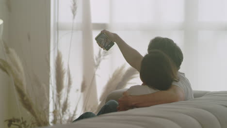 vista posterior de una pareja feliz haciendo una selfie en casa. una pareja joven tomando una foto.