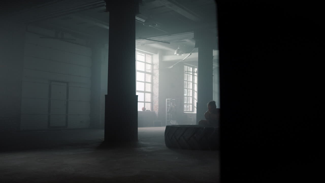 hombre volviendo el neumático durante el entrenamiento en el gimnasio. atleta masculino levantando un neumático de goma pesado
