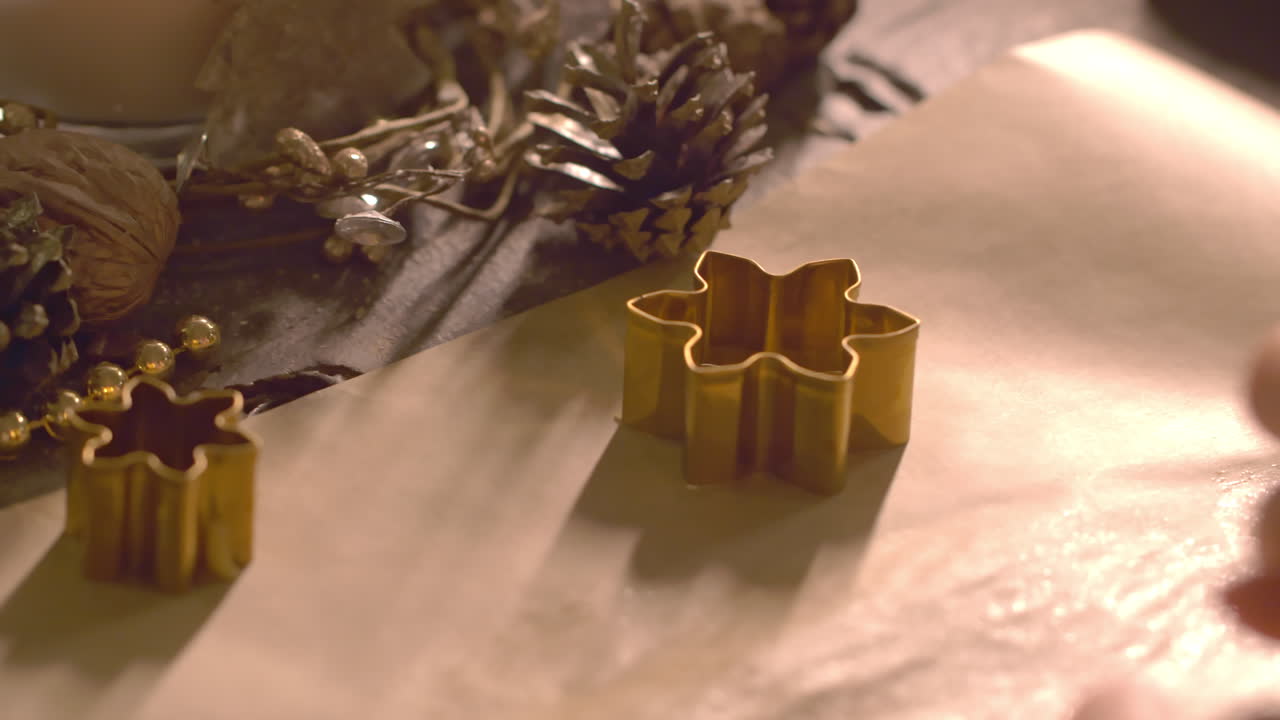 Handheld, snow flake shape cookie cutter on baking sheet around Christmas decor