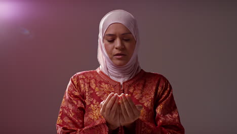 studio head and shoulders portrait of muslim woman wearing hijab praying 10