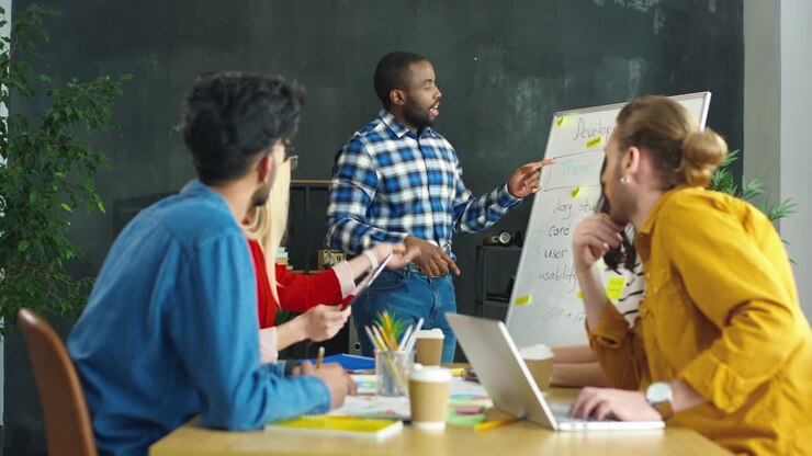 Jeune homme expliquant la stratégie et le développement commercial à un groupe de jeunes entrepreneurs multiculturels lors d'une réunion au bureau.