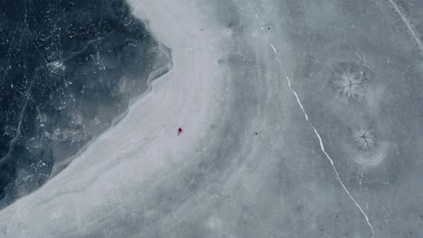 person ice skating on frozen lake drone aerial in winter