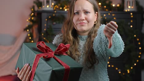 woman's thumbs-down reaction to an unwanted christmas present, festive background at home