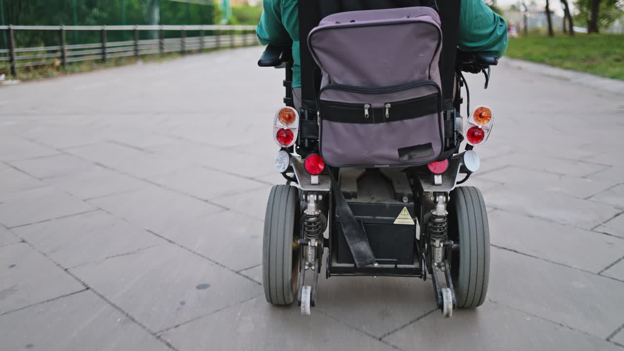 Person Riding Electric Wheelchair on a Paved Path in a Park