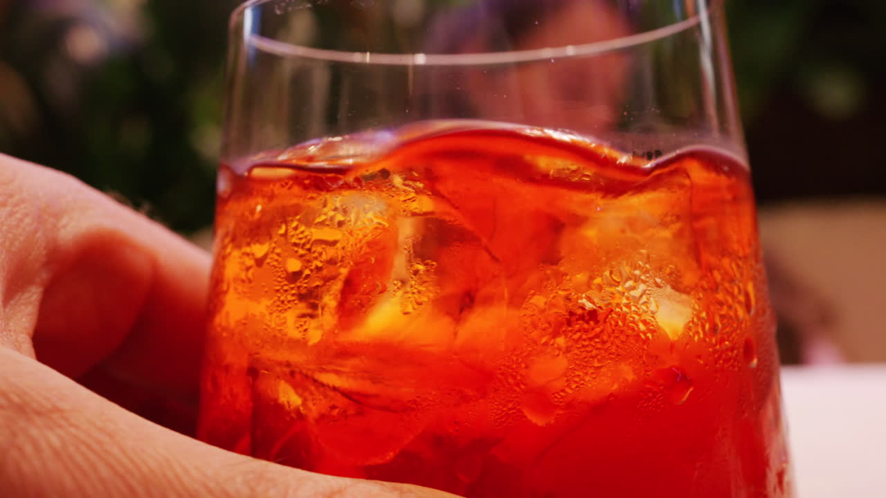 Primo piano macro dettagliato di un cocktail rinfrescante con cubetti di ghiaccio e goccioline d'acqua sulla superficie del bicchiere