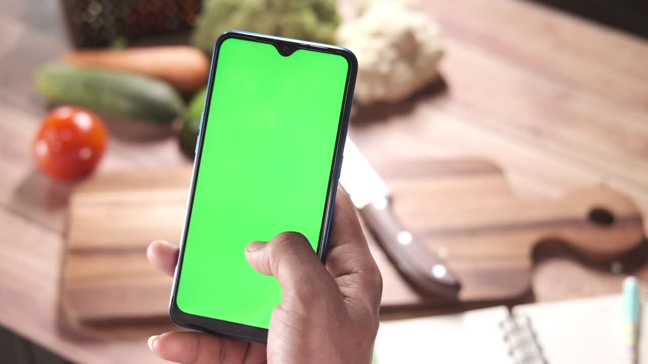 vista superior de un joven usando un teléfono inteligente y verduras en el fondo