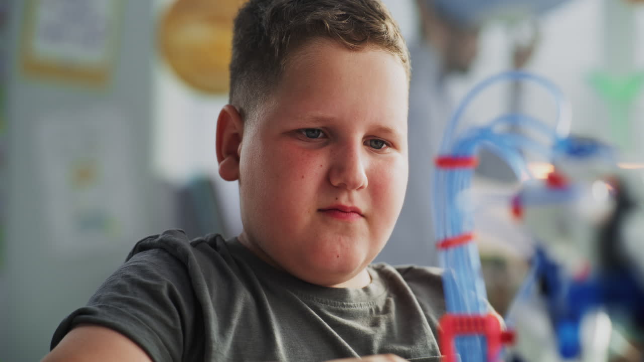 Close Up of Elementary School Boy Examining Model of Innovative Robotic Arm