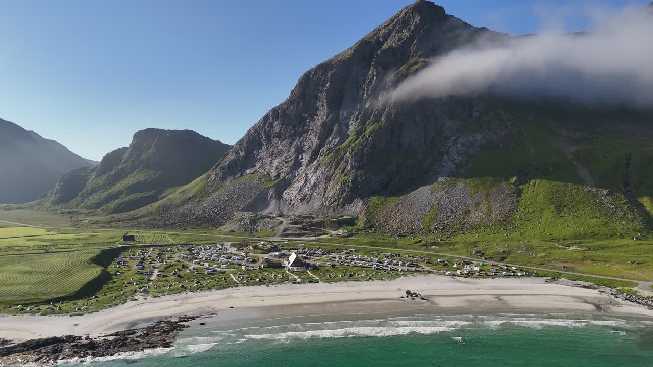 A breathtaking morning view of Flakstadsanden Beach, featuring pristine white sand and a towering mountain nearby topped with a small cloud
