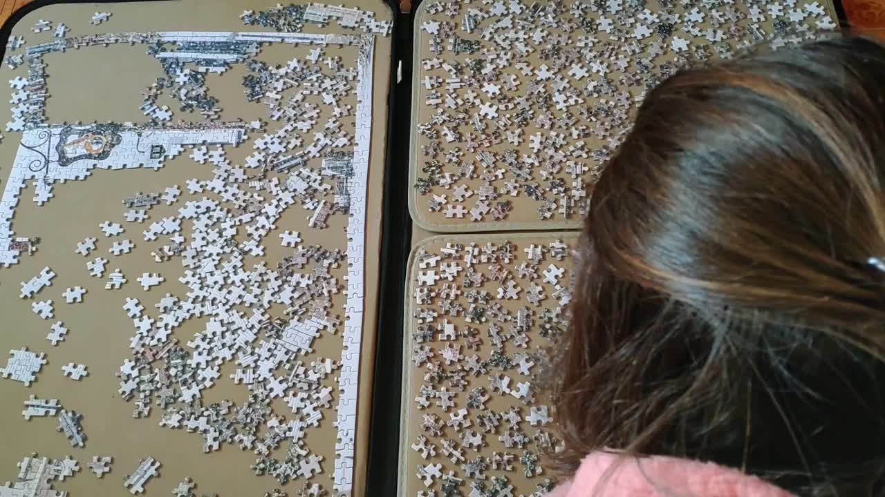 Top view of a woman on comfortable clothes at hme working on a big puzzle