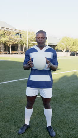 vertical video: rugby player holding ball on field, focused and ready for game