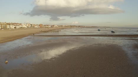 Golden-sandy-beach-with-boats-and-sand-traps-at-low-tide-in-the-UK