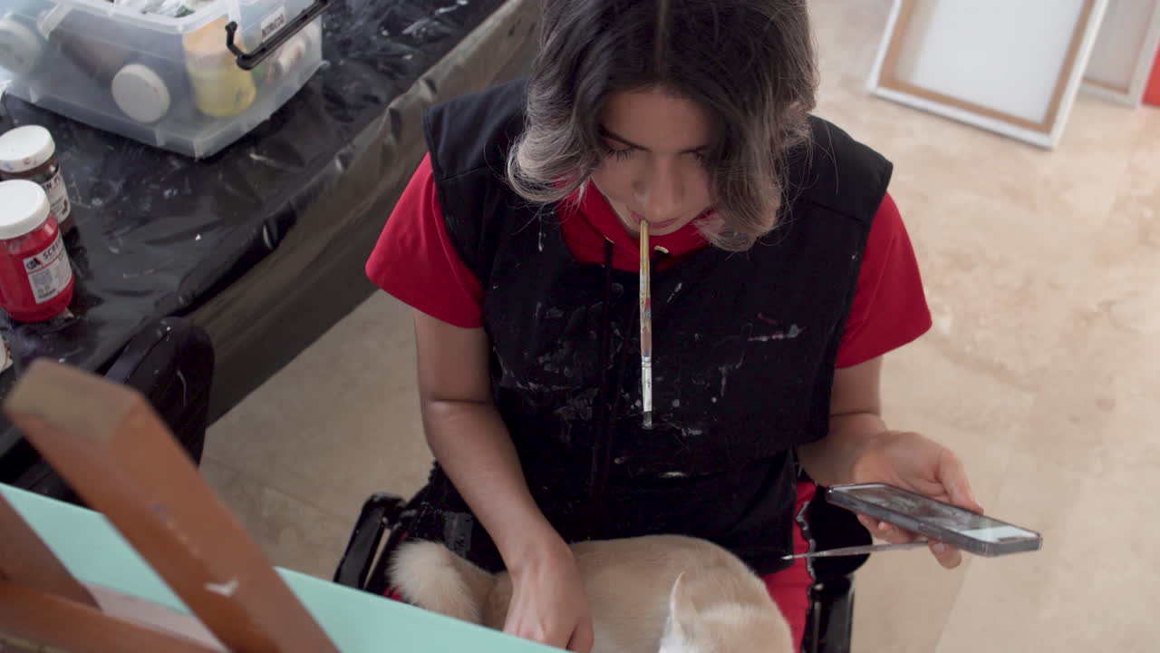 Young female artist painting on canvas with passion, close up handheld view