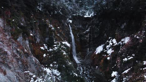 A-tranquil-aerial-view-of-a-winter-mountain-forest-with-a-waterfall-running-through-the-landscape-in-Patagonia