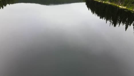 dolly and tilt aerial view of a small lake in bighorn national forest in wyoming on a calm cloudy summer morning