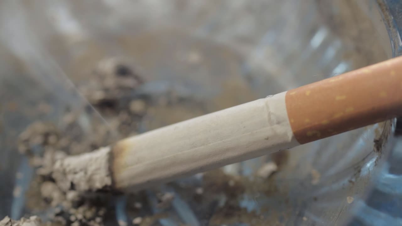 Lit cigarette smoking and burning away in an ashtray