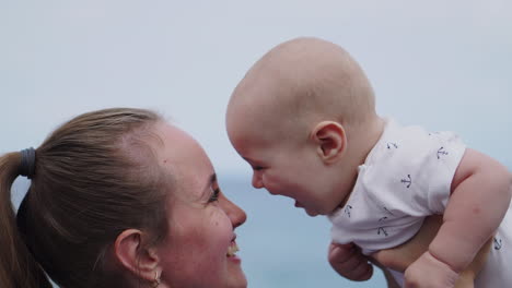 against the ocean backdrop, the mother lifts her son high with playful tosses in the air, amplifying the enjoyment of their time on the seashore. a content young family relishes the beach